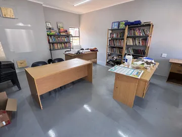 Another classroom set up with wooden desks and shelves of donated books along the walls.