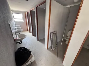 A new bathroom block with a row of basins along one wall and tiled toilet cubicles.
