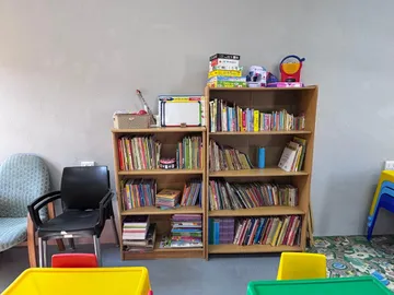 Two wooden bookcases packed with picture books and board games in the younger children's room.