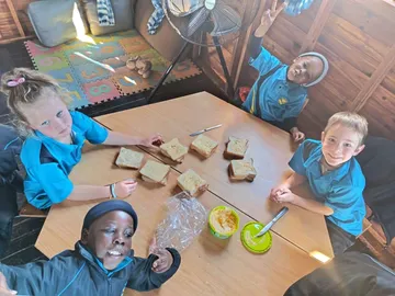 Children from Dullstroom Primary School around a table making sandwiches to bring to the centre.
