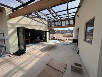 A covered outdoor courtyard between two wings of the building, still being finished, with folding doors opening into a classroom.