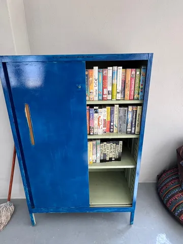 A blue metal cabinet holding a collection of donated films on VHS and DVD.