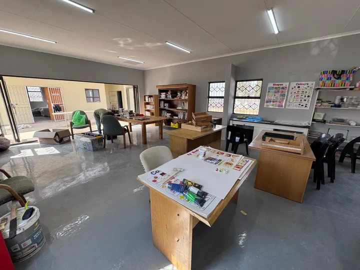 A large open classroom with desks, chairs, bookshelves and colourful wall charts.