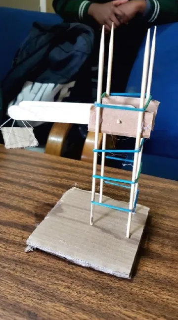 A model crane with a cardboard counterweight and a string-hung platform.