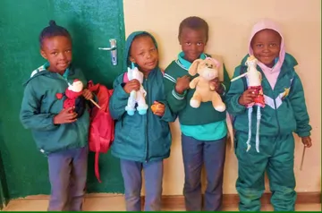 Four of our youngest children in school tracksuits, each holding a donated soft toy.