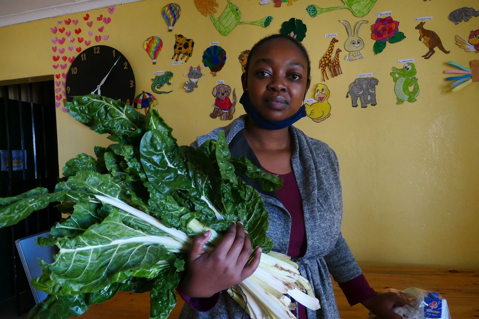 Simphiwe Skhosana holding a bunch of spinach at the Dullstroom Community Centre during the 2020 lockdown.